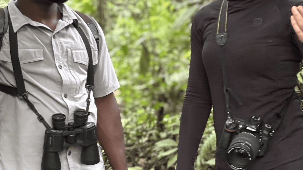 Mwanzo guide with binoculars and a trekker with a camera in the forest