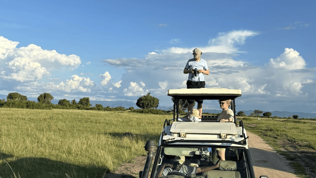 Guest standing in the open roof of a safari vehicle on the savanna